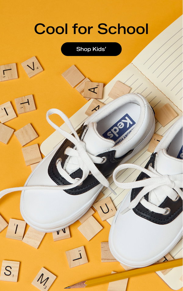 A pair of Kid’s School Day II Lace-Ups in white sitting on top of lined notebook paper with Scrabble letter tiles scattered around them. Text above the sneakers says Cool for School. Shop Kids’.