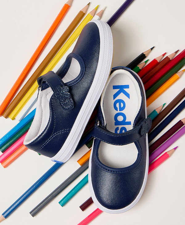 A pair of Little Kids’ Ella Mary Jane sneakers in navy sitting on top of an array of bright colored pencils.