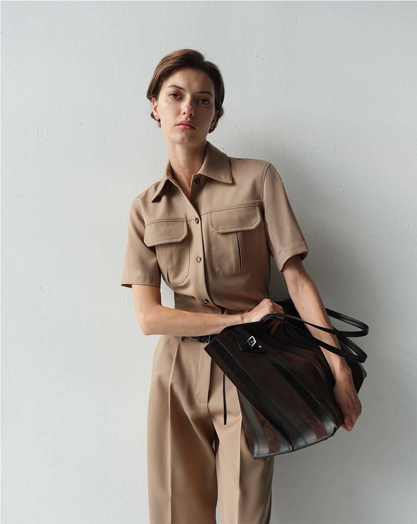 Cropped image of model wearing Nali Top in Wool Gabardine in Khaki and the Halima Pant in Wool Gabardine in Khaki with the Days Carryall in Calf Striped Intarsia in Black/Espresso