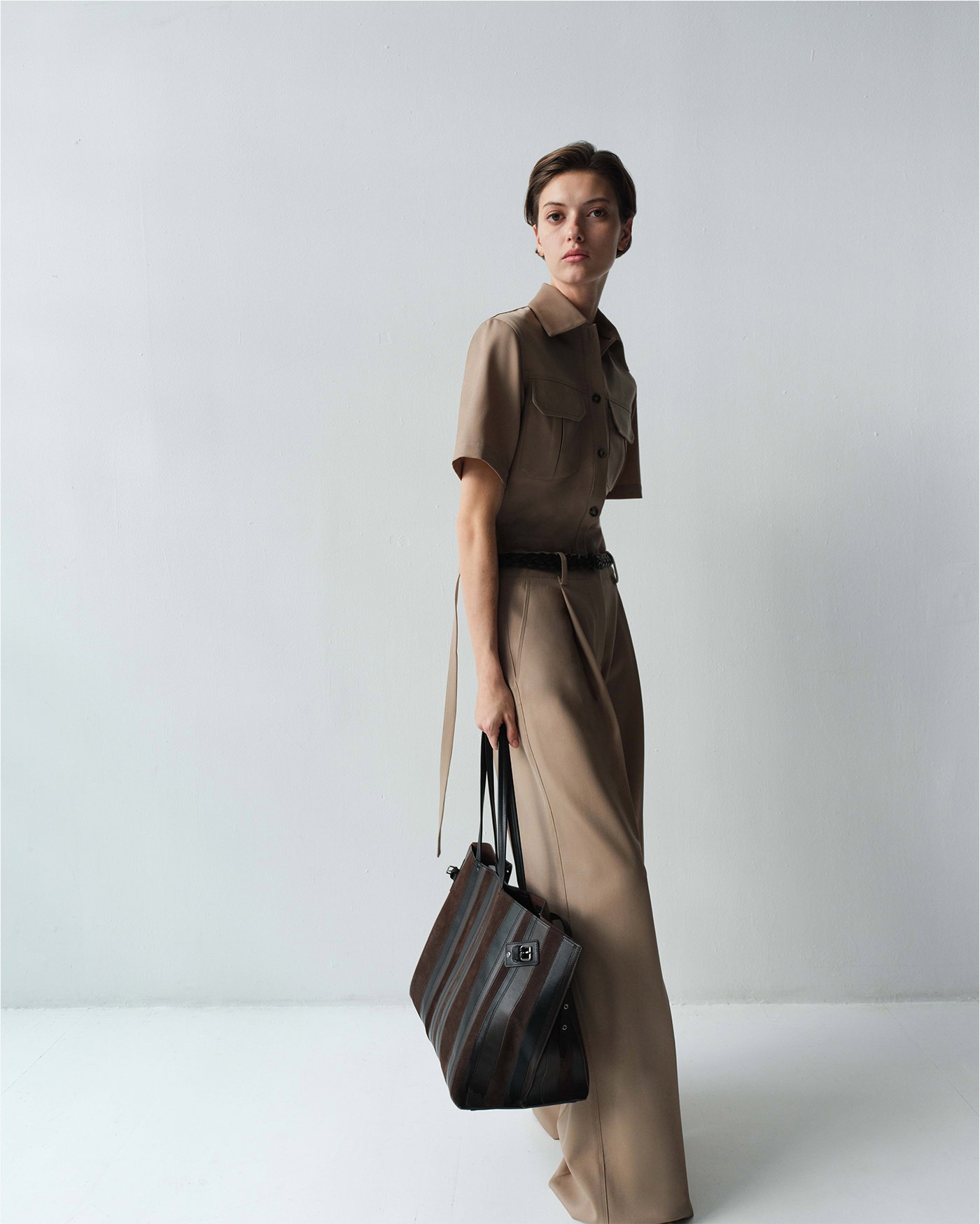 Image of model wearing Nali Top in Wool Gabardine in Khaki and the Halima Pant in Wool Gabardine in Khaki with the Days Carryall in Calf Striped Intarsia in Black/Espresso