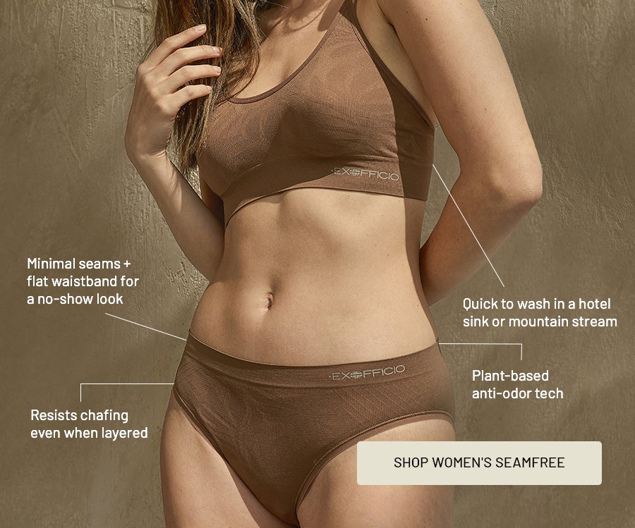Woman wearing a brown SeamFree bralette and briefs, with callouts: minimal seams plus flat waistband for a no-show look; resists chafing even when layered; quick to wash in a hotel sink or mountain stream; plant-based anti-odor tech. Button: Shop Women's SeamFree.