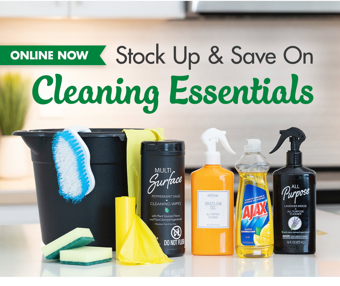 Stock Up & Save On Cleaning Essentials. Image of a bucket, scrub brush, dish soap, sanitizing wipe, sponges, and cleaning sprays on a kitchen counter.