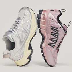 Een paar sportschoenen, de linker metallic zilver met een crèmekleurige zool, de rechter roze met zwart veterwebbing, staand zool-op-zool op een neutrale achtergrond.