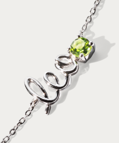 A silver love script bracelet with a green peridot gemstone accent.