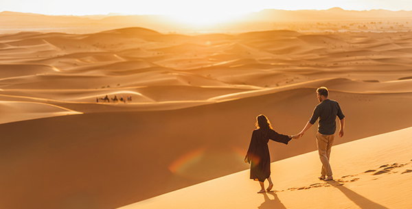 Paar läuft eine Sanddüne in der Wüste hinab.