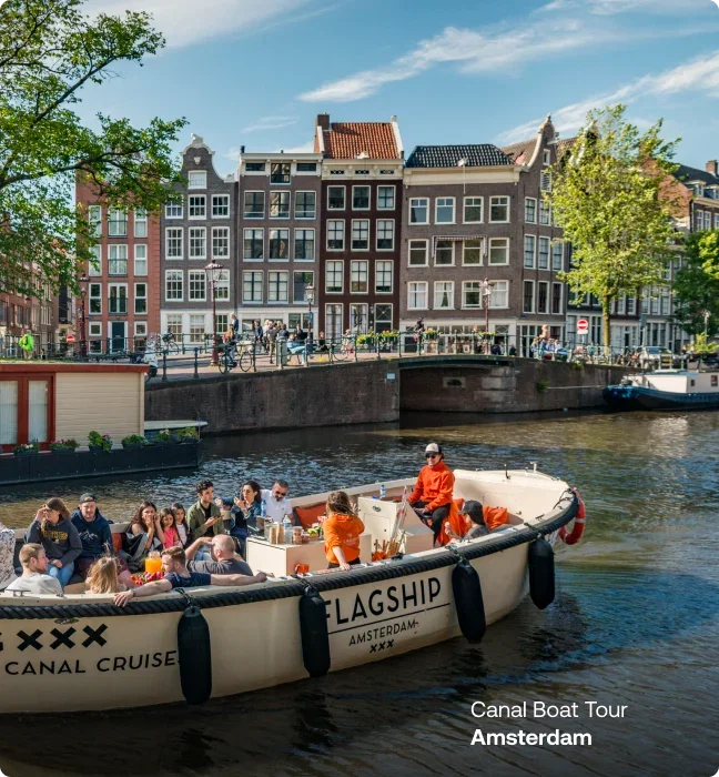 Group enjoying a canal boat tour past Amsterdam's historic canal houses.