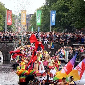 Boats and crowds celebrating at Amsterdam's Pride canal parade.