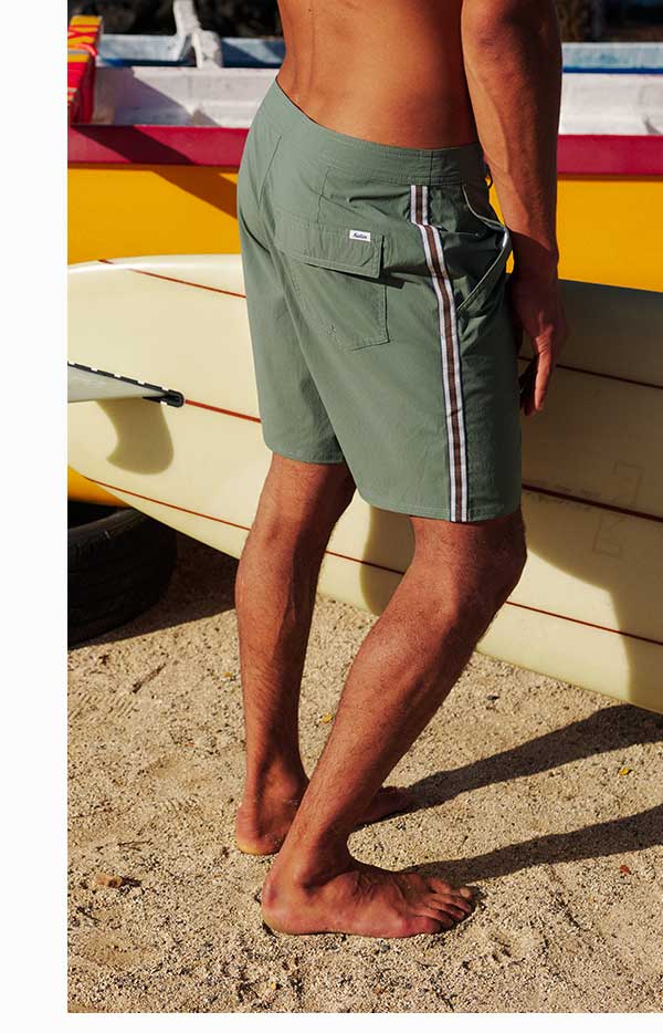 Man wearing the Theo Hybrid Trunk and holding a surfboard