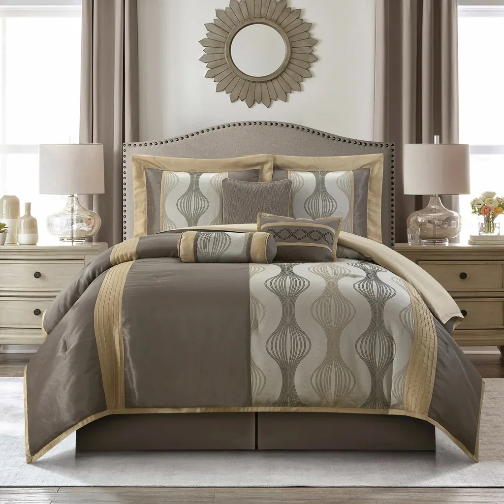 Elegant bedroom with gray upholstered headboard, taupe and cream bedding set, matching nightstands with lamps, and sunburst mirror.