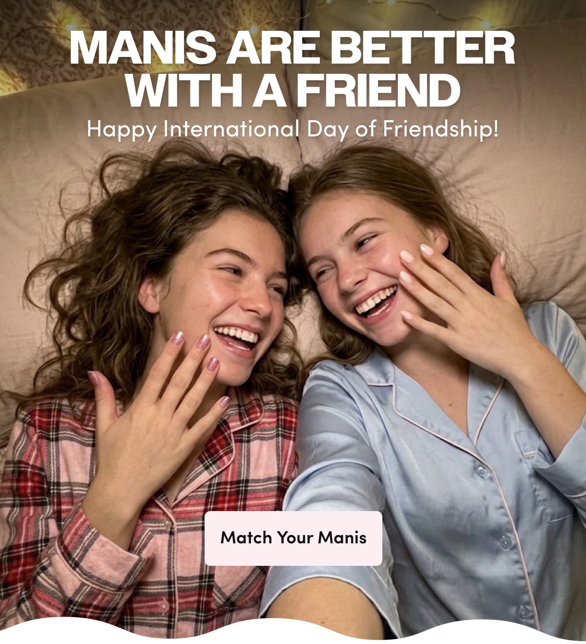 'Mani's Are Better With A Friend — Happy International Day of Friendship!' promo graphic showing two laughing friends lying on a bed in pajamas, showing off their manicured nails in pink shimmer and white polish, with string lights in the background.