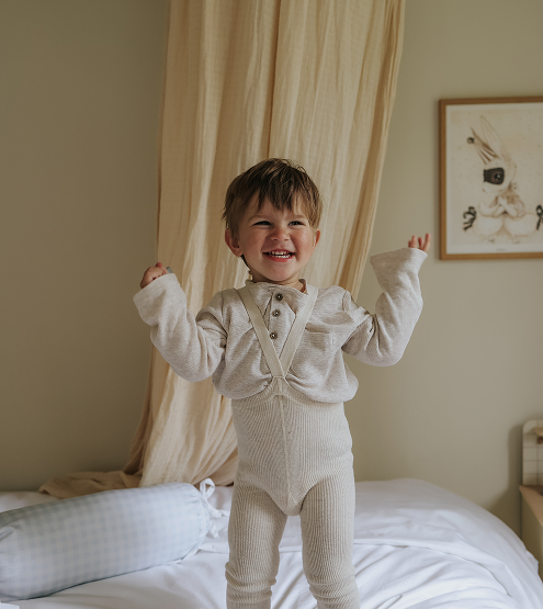 kid standing on top of bed