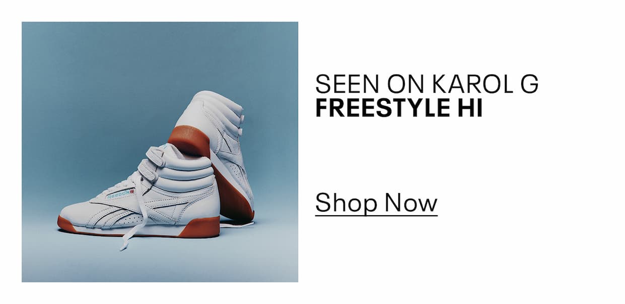 Pair of white Freestyle Hi sneakers displayed against a blue background. Text reads: “SEEN ON KAROL G. FREESTYLE HI. Shop Now.”