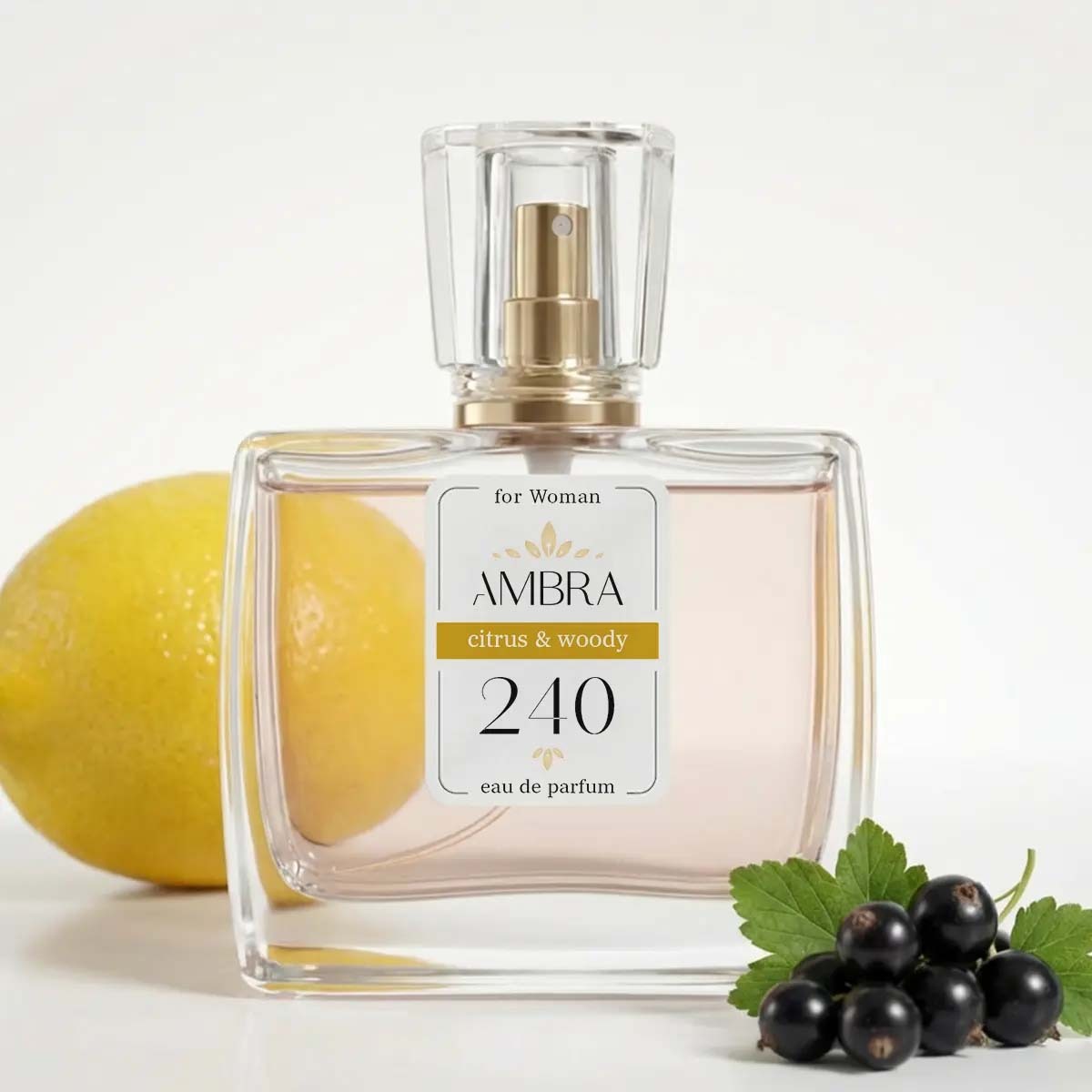 Glass bottle of Ambra 240 eau de parfum for women, citrus & woody scent, with lemon and blackcurrants beside bottle