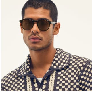 Image of man wearing round tort sunglasses looking at the camera