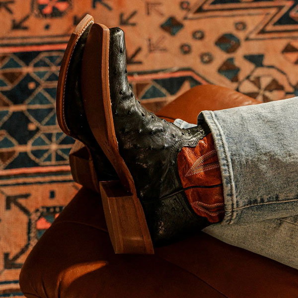 Man sitting with fit on foot stool wearing a pair of Tony Lama boots.