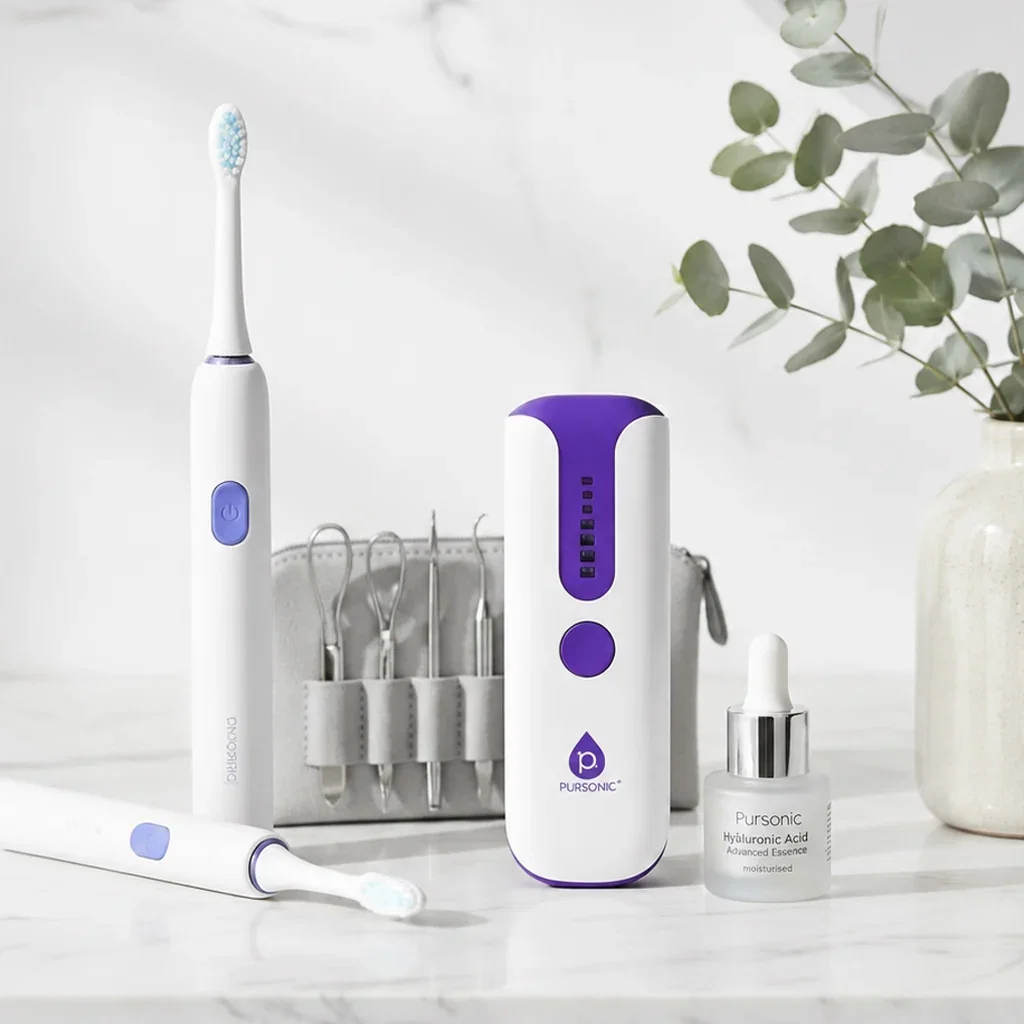 Pursonic self-care collection featuring electric toothbrush, oral irrigator, skincare serum, and dental tools on marble surface with eucalyptus.