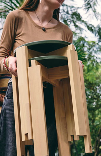A women carying the set of two KOMPISHÄNG stools through the park.