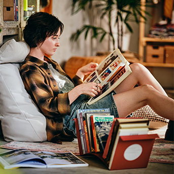 A person reading a book in bed with the KOMPISHÄNG book-end next to them full of other books.
