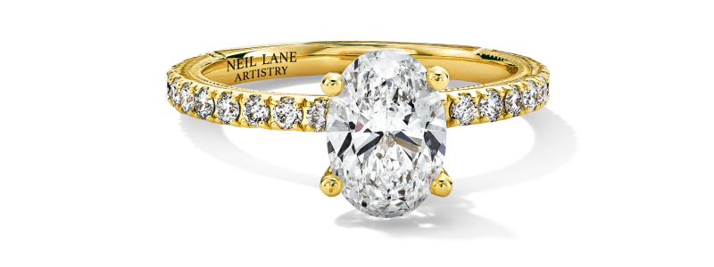 An oval diamond engagement ring with pavé band in yellow gold.