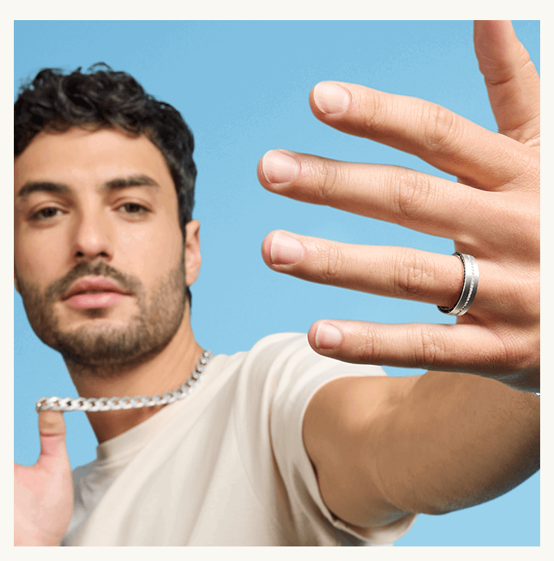 Male model wearing polished silver ring band with diamond details & thick silver chain necklace.
