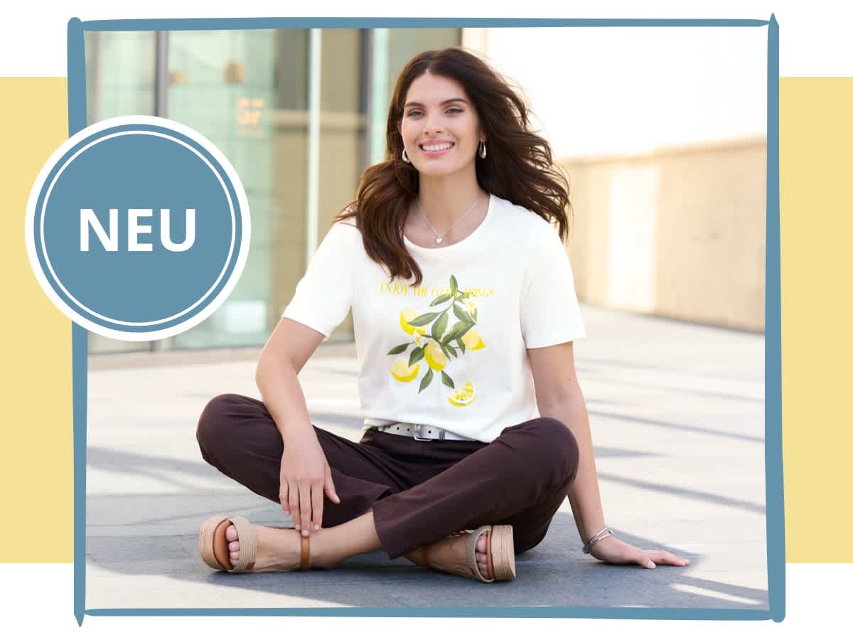 Ein Model sitzt draußen auf dem Boden, trägt ein weißes T-Shirt und braune Hose. Die neue Kollektion. Alle Größen ein Preis. Bild oder Schaltfläche darunter anklicken, um in den Shop zu gelangen >