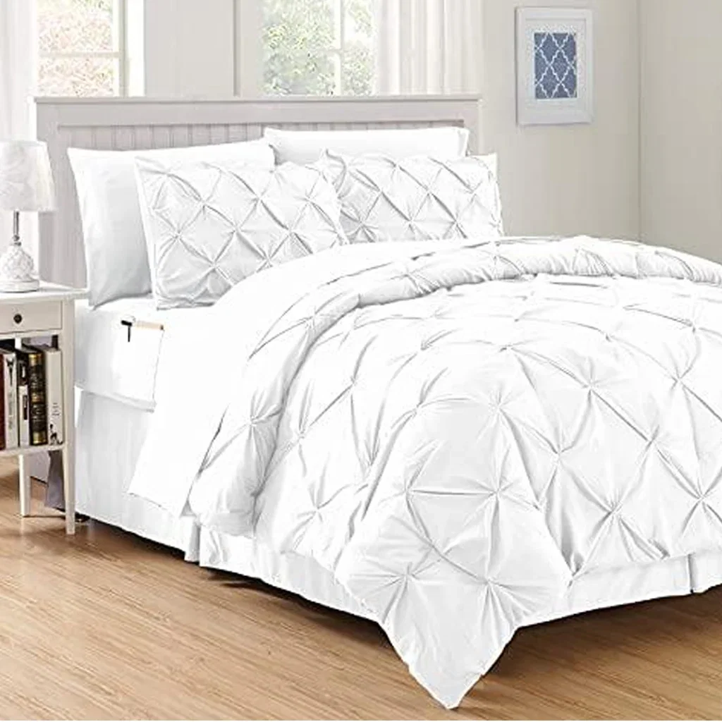 White pinched pleat comforter set with matching pillows on wooden bed frame in bright bedroom.
