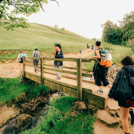 People crossing a wooden bridge over a small stream.