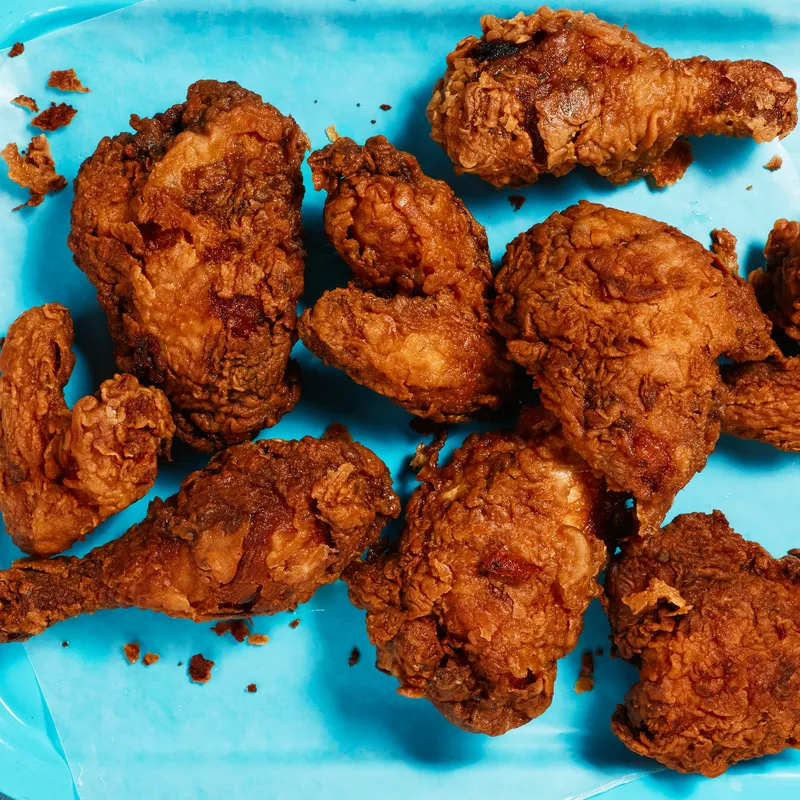 Several pieces of golden skillet-fried chicken on a blue serving tray.