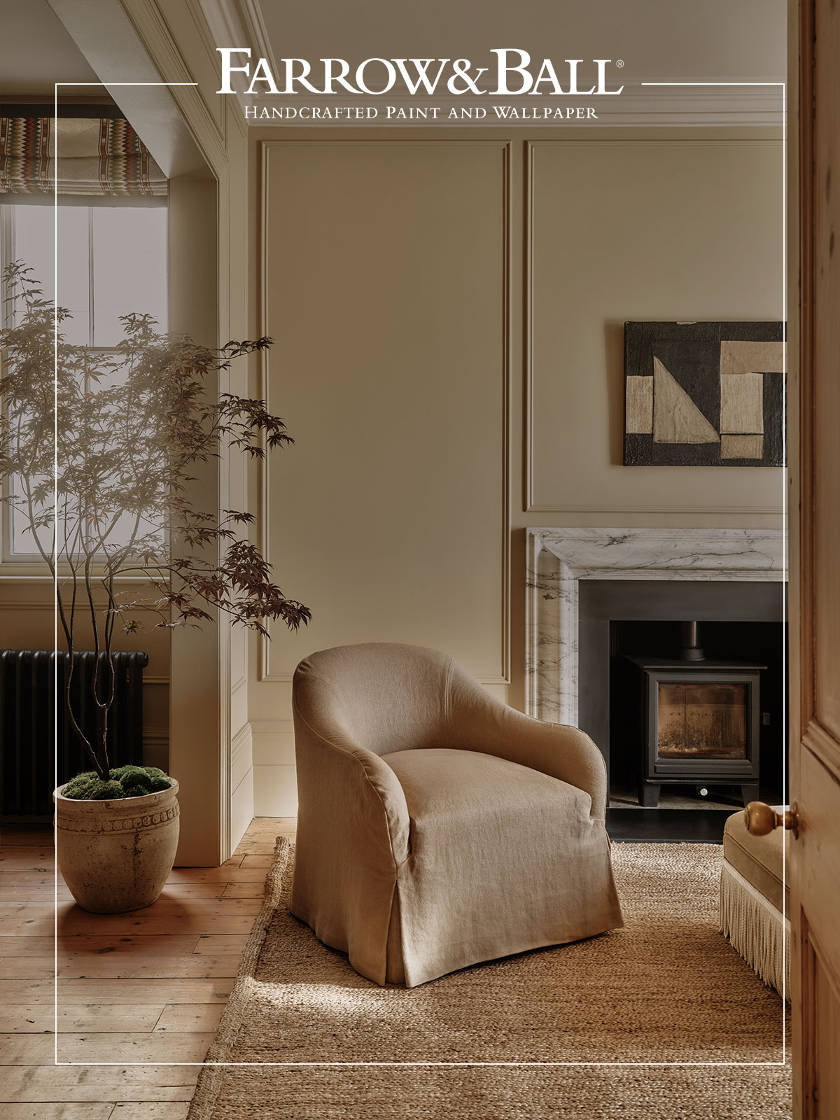 Neutral sitting room with beige walls, linen armchair, marble fireplace, and wooden floor.