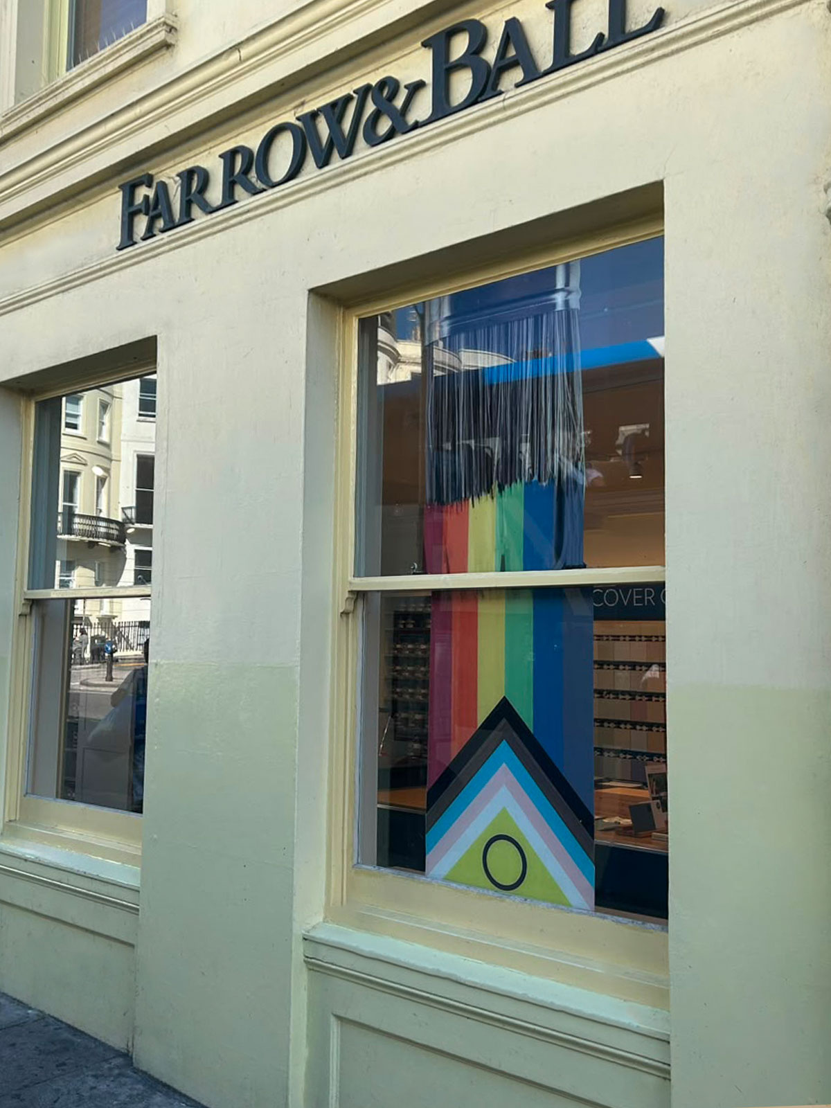 Farrow & Ball shopfront with cream walls and a window display featuring a colourful geometric Pride design.