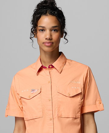 A woman wearing a light orange button-up short sleeve shirt.