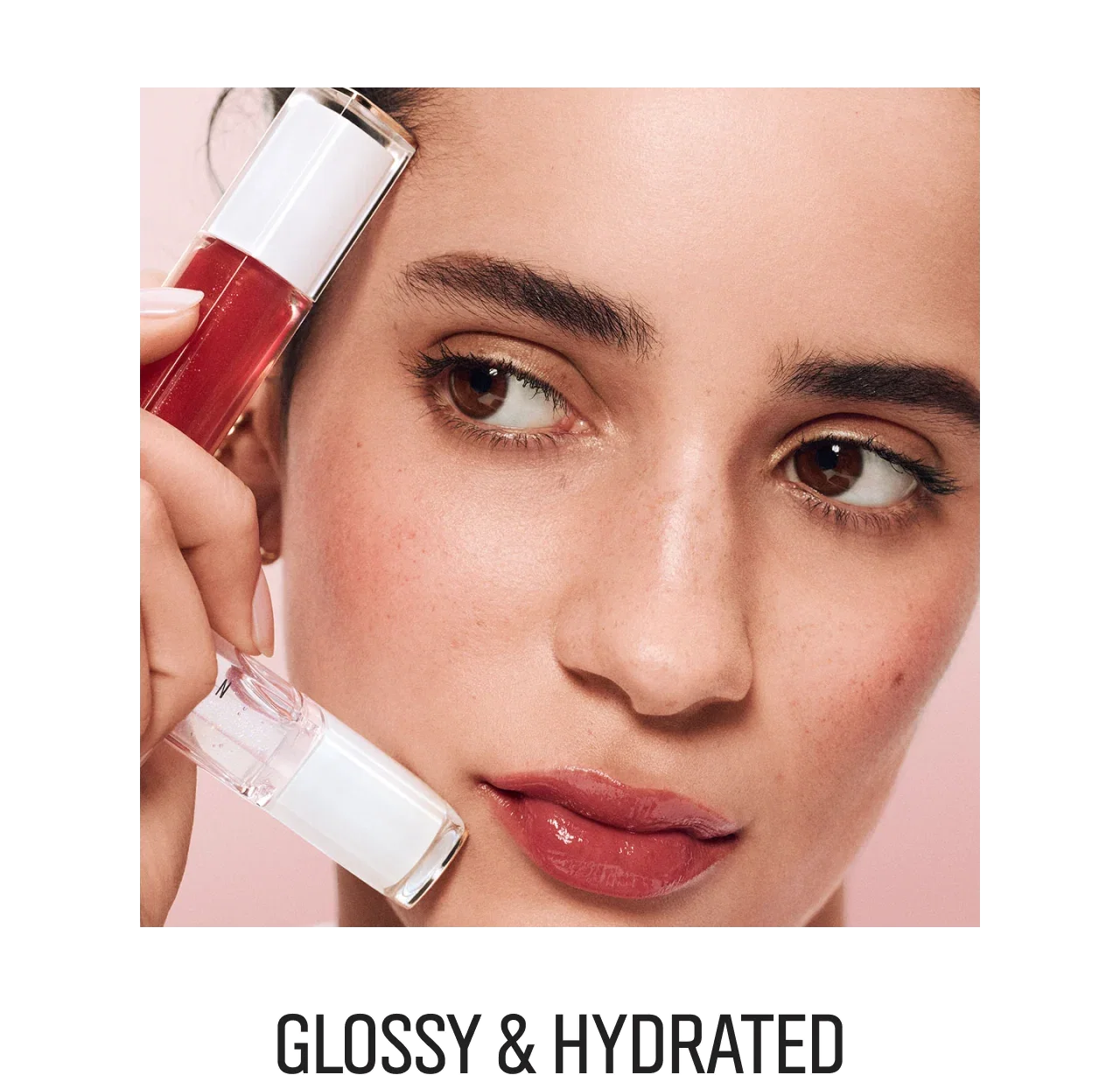Close-up of a woman holding Extra Lip Tinted Balm and Extra Blushing Lip Oil.