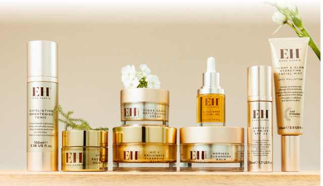 Emma Hardie skincare collection displayed on a softly lit shelf with white flowers.