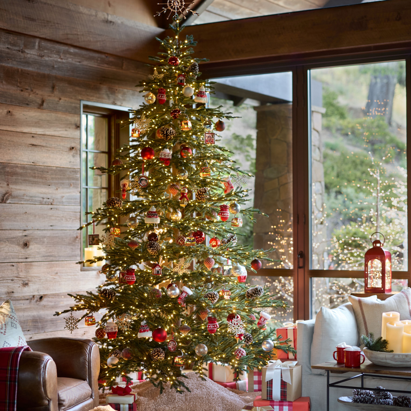 Pre-lit Christmas tree decorated with red and gold baubles in a cosy living room with wrapped gifts underneath.