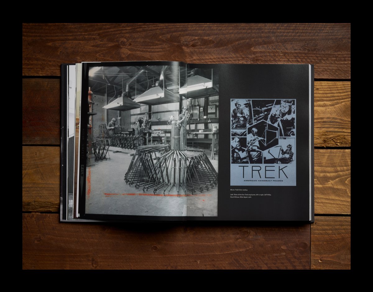 An open spread from the Trek 50th Anniversary Book showing black-and-white photos of the original Trek factory and workers building bicycle frames