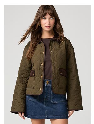 A woman wearing an olive green padded jacket with quilt detail.