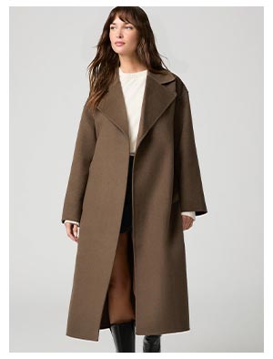 A woman wearing a brown trench coat, whit shirt and black skirt.
