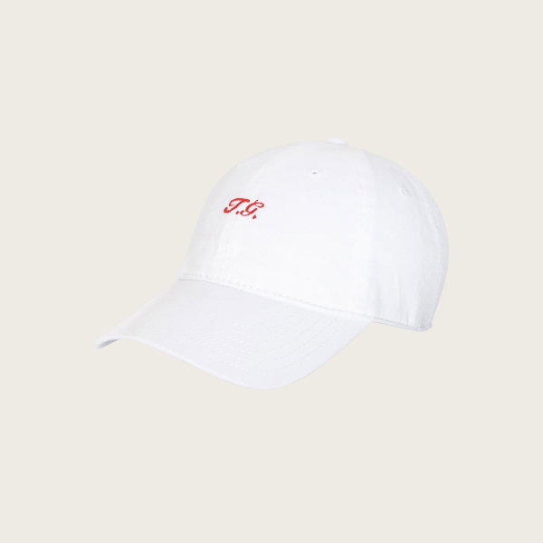 The Baseball Hat in white by THE GREAT. SU26 features "T.G." embroidered in red on the front, displayed on a plain white background.