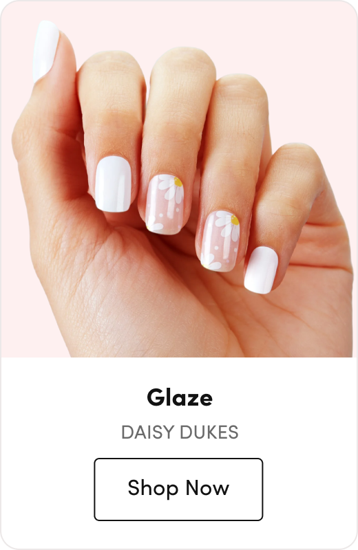 Hand with white nail polish featuring daisy flower accent nails, labeled 
