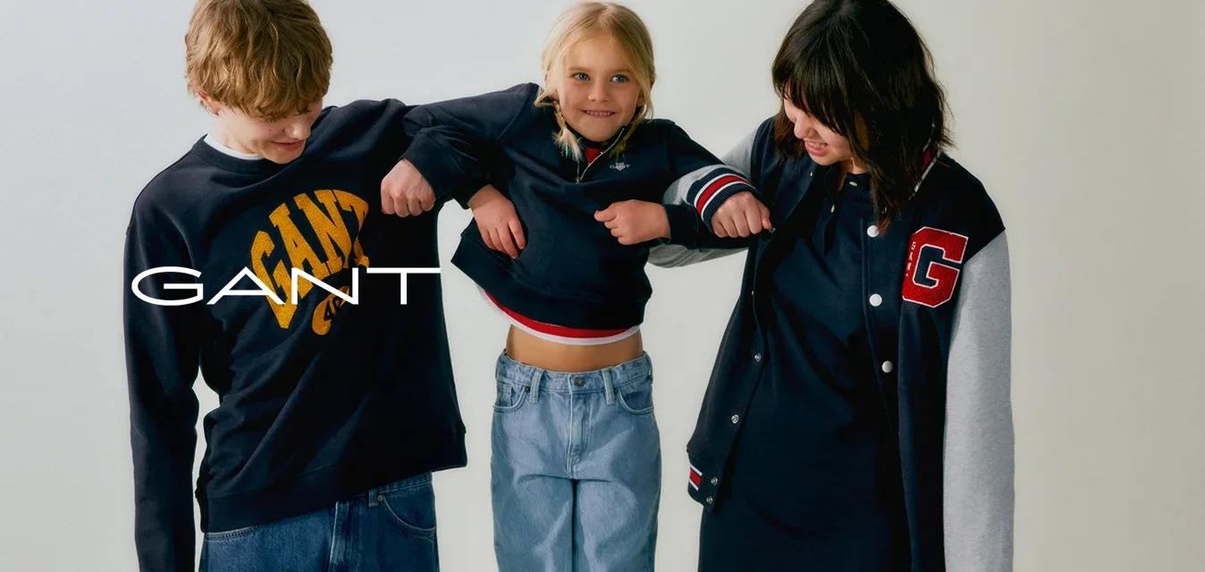 Due adolescenti e un bambino sono in piedi su una sedia. Gli adolescenti indossano felpe scure; uno ha un logo. Il bambino indossa un top corto e jeans chiari.