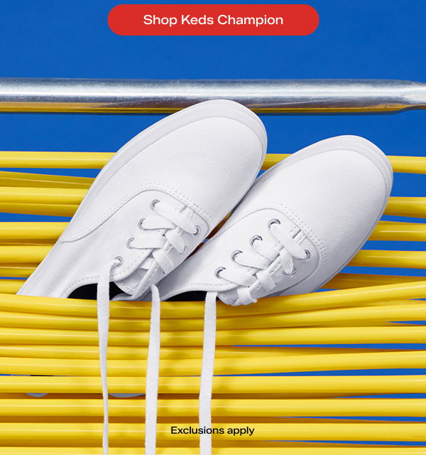 A pair of Original Keds Champion Canvas Lace-Ups in white nestled in between the webbing of a yellow beach chair.