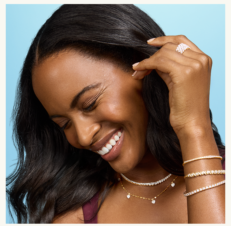 Model smiling in layered gold & diamond chains & bracelets.