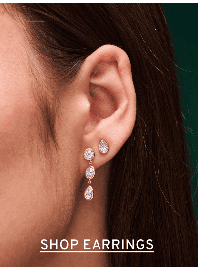 Close up of diamond earrings in woman’s ear. Click to Shop Earrings
