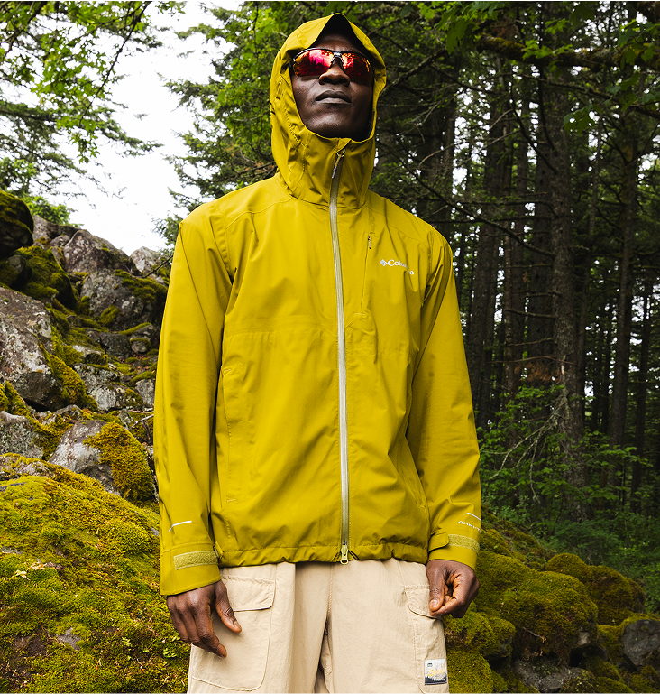 A man wearing a lightweight Columbia rain jacket with the hood on. 
