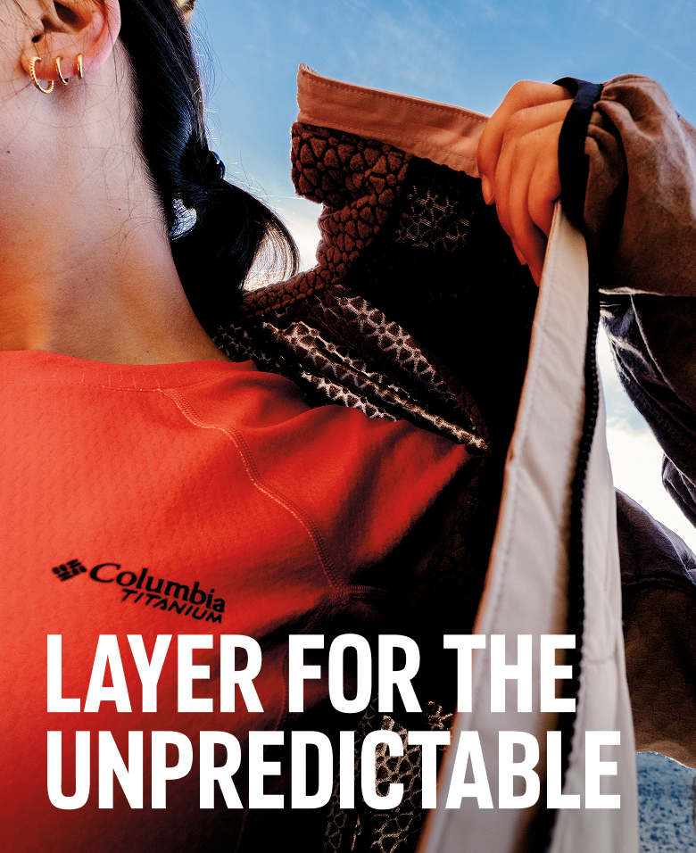A woman wearing a Columbia Titanium shirt puts on her jacket featuring Omni-Heat technology.