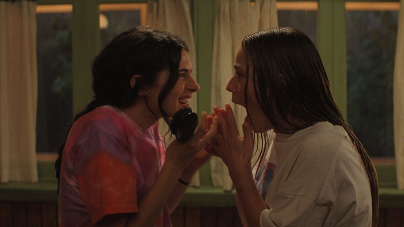 Friends laugh face-to-face in a warmly lit room