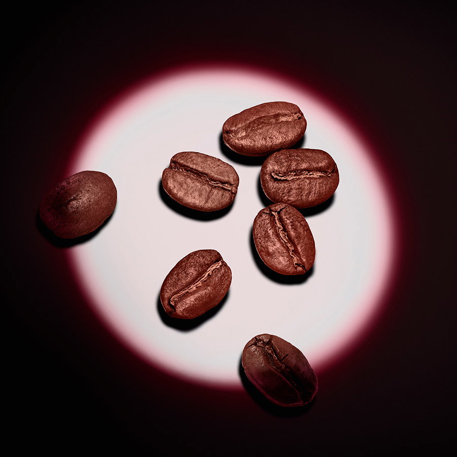 Six roasted brown coffee beans illuminated by a circular spotlight on a black background.