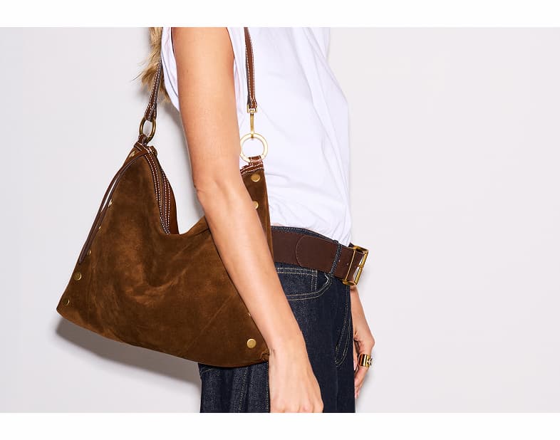 Side profile of the Hammitt Kyle Lrg in Cinnamon Suede, showcasing soft Italian suede, leather trim, brushed gold hardware, signature rivets, and a removable shoulder strap.