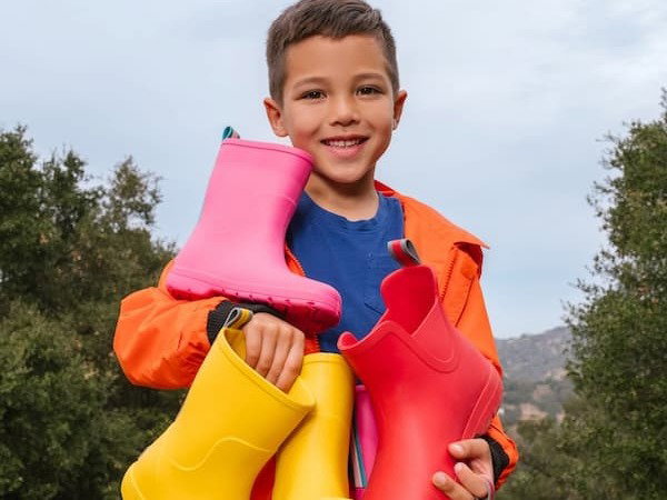 Boy holds several pairs of colorful totes rain boots