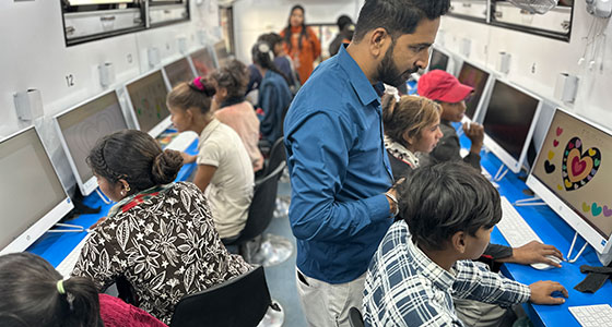 Kinder und Jugendliche sitzen im digitalen Lernbus der SOS-Kinderdörfer in Indien vor Computern - Foto: Christine Kehrer